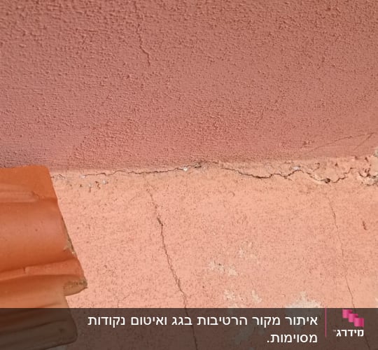 רעפים חומים על גג עם קיר ורוד סדוק